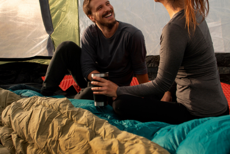 Pareja encima de sus sacos de dormir mientras conversan