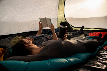 Persona encima de su colchon inflable mientras lee un libro